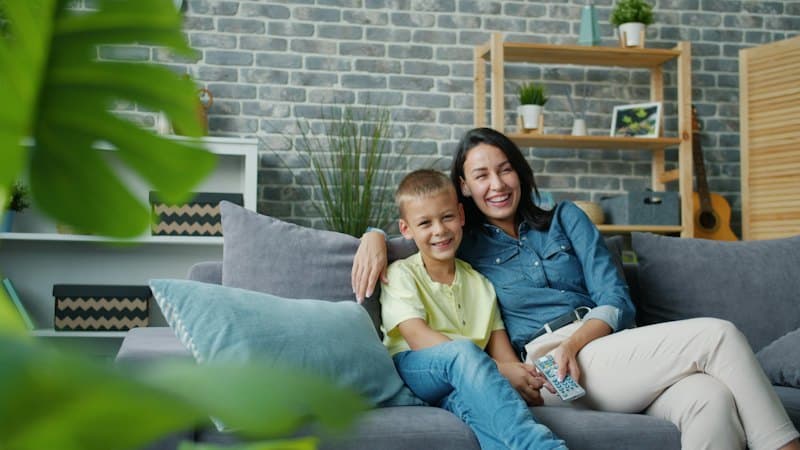 Mãe e filho sorrindo no sofá da sala de casa